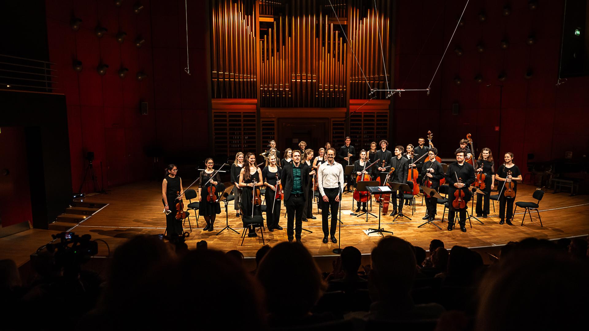 Studioorchester vor der beleuchteten Orgel im Konzertsaal.