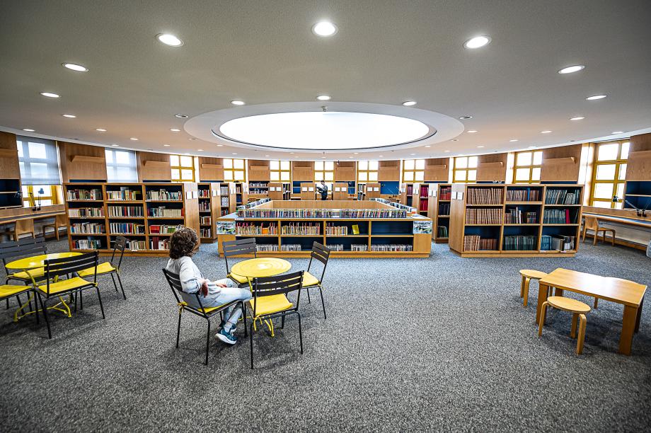 Auf dem Bild ist das obere Stockwerk der Bibliothek mit Sitzplätzen und Bibliotheksregalen zu sehen.