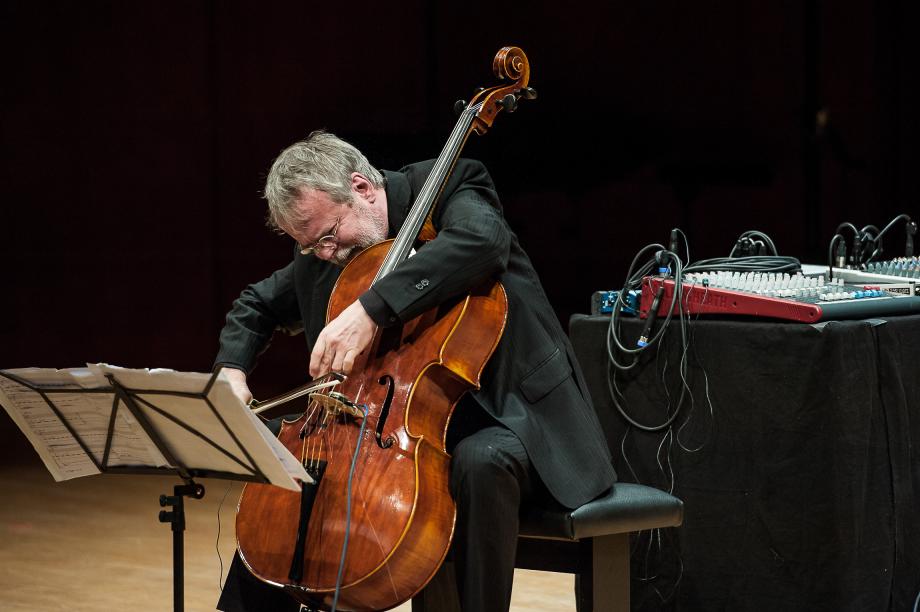 Violoncelloprofessor Conradin Brotbel bei der Uraufführung einer modernen Komposition. In unmittelbarer Nähe zu ihm steht eine PA-Anlage.
