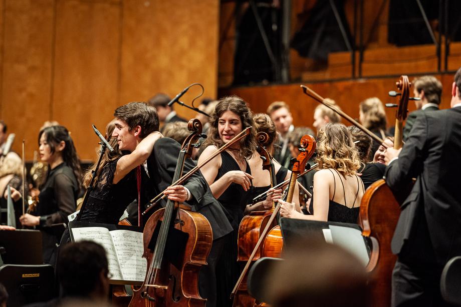 Die Mitglieder der Streichergruppe umarmen und gratulieren sich nach dem gemeinsamen Konzert des Hochschulsinfoneiorchesters.