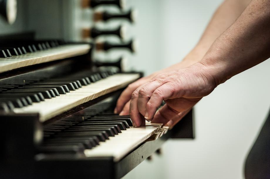Detailaufnahme von zwei Händen auf einer dreimanualigen Orgel.