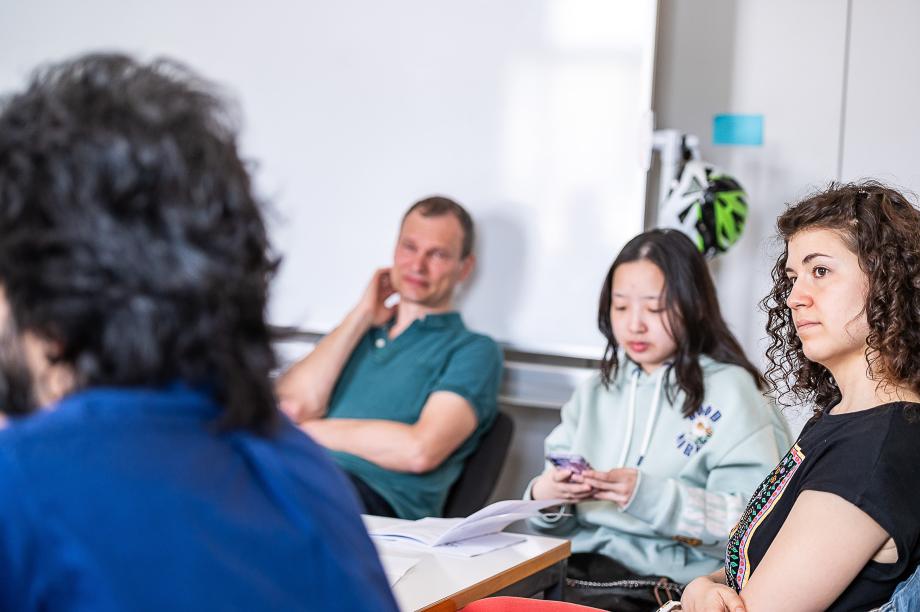Studierende sitzen gemeinsam um einen Tisch und sind im Gespräch.