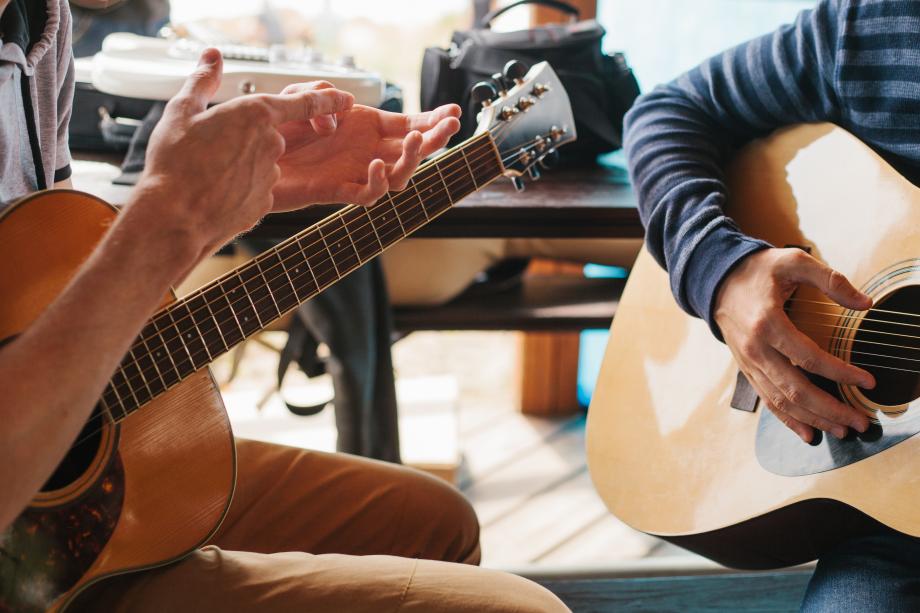 Fokus auf Hände der Studierenden an ihren Gitarren.