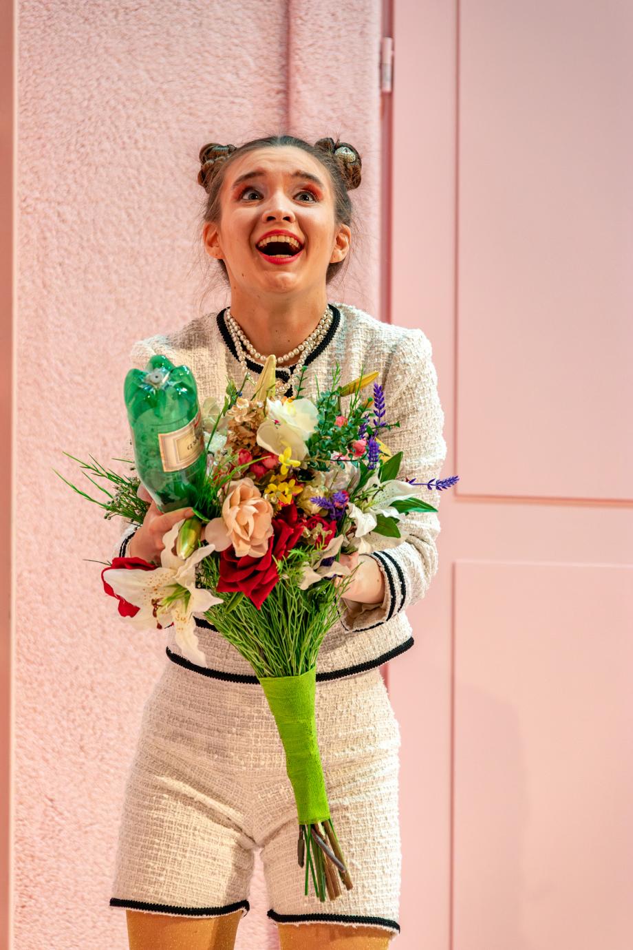 Frau mit Blumenstrauß und Flasche, lachend