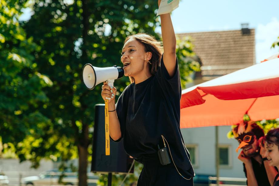 Frau mit Mikro-und Megaphon auf einer Demonstration.